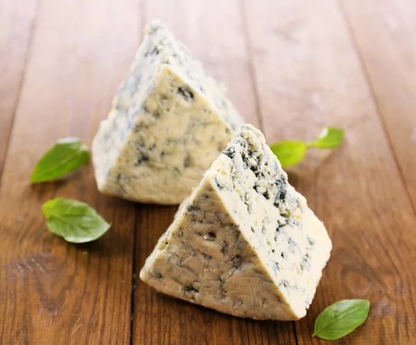 Sabroso queso azul con albahaca, sobre mesa de madera — Foto de Stock