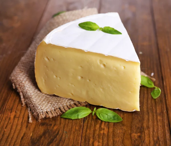 Sabroso queso Camembert con albahaca, sobre mesa de madera —  Fotos de Stock