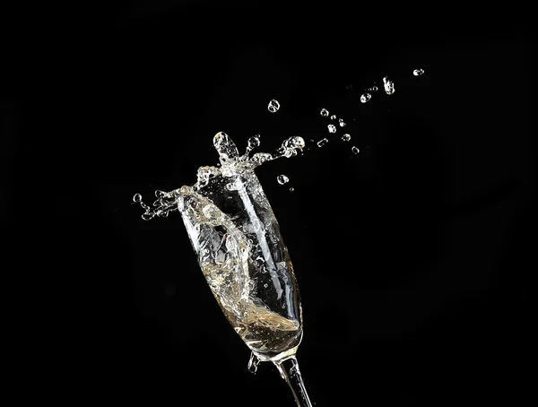 Glass of champagne with splash, on black background — Stock Photo, Image
