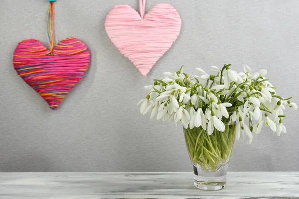 Красивые подснежники в вазе с сердцами на сером фоне — стоковое фото