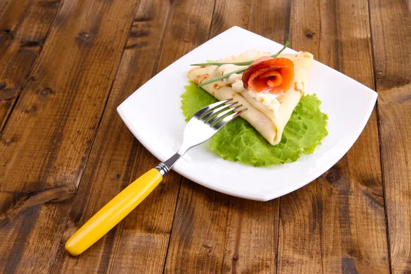 Pancake with salmon, and mayo, green onion, on plate, on wooden background — Stock Photo, Image