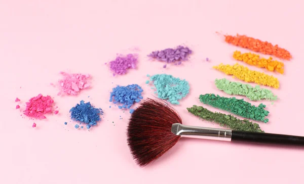 Rainbow krossade ögonskugga och professionella make-up pensel på rosa bakgrund — Stockfoto