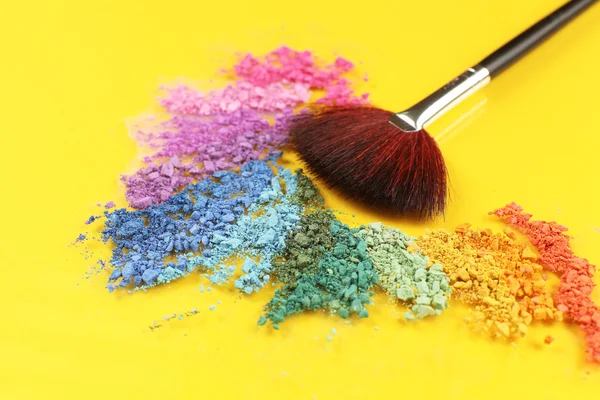 Arco iris triturado sombra de ojos y maquillaje profesional cepillo sobre fondo amarillo —  Fotos de Stock