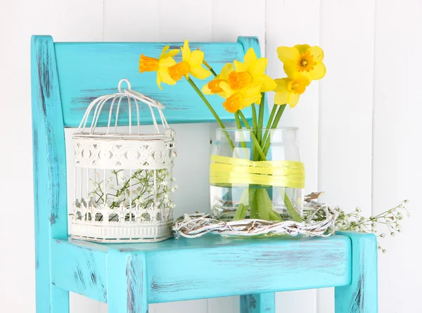 Beautiful spring flowers on blue old wooden chair — Stock Photo, Image