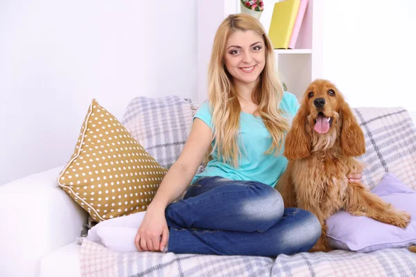 Beautiful young woman with cocker spaniel on couch in room — Stock Photo, Image