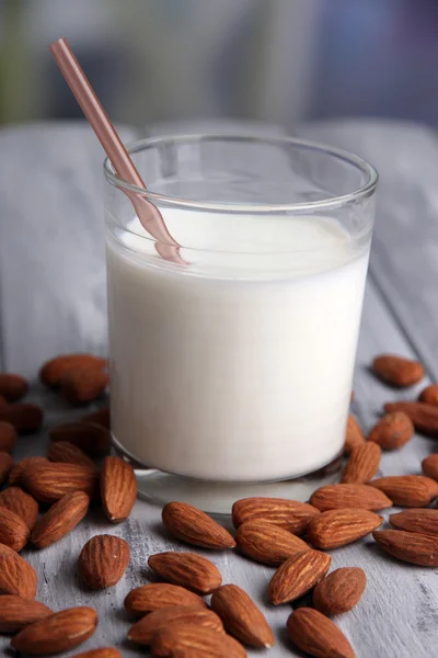 Lait d'amande en verre aux amandes, sur table en bois de couleur, sur fond lumineux — Photo