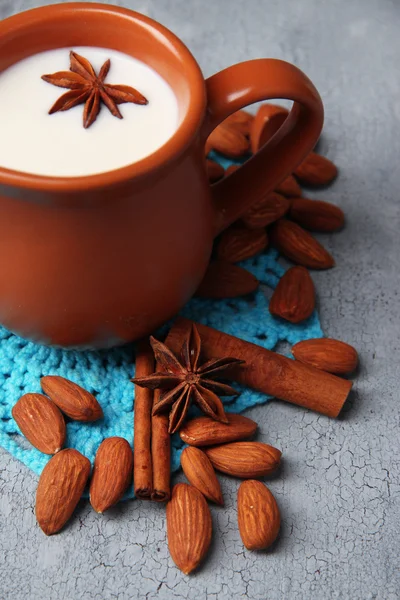 Latte di mandorla in brocca con mandorle in ciotola, su sfondo di legno a colori — Foto Stock