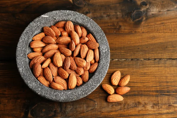 Almond dalam mangkuk pada warna latar belakang kayu — Stok Foto