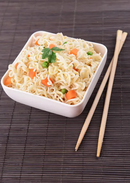 Sabrosos fideos instantáneos con verduras en un tazón en la mesa de cerca —  Fotos de Stock