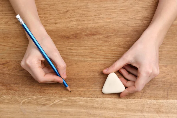 人类的手，用铅笔和擦除橡胶木桌背景 — 图库照片