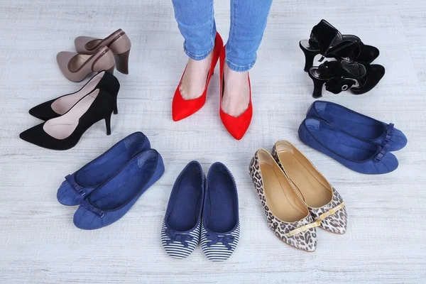 Dziewczyna wybiera buty w pokoju na szarym tle — Zdjęcie stockowe
