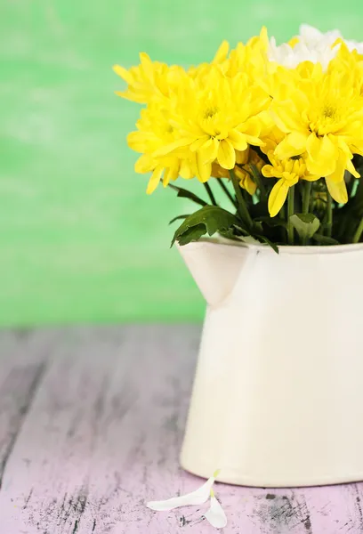Beautiful chrysanthemum flowers in pitcher on wooden table — Stock Photo, Image
