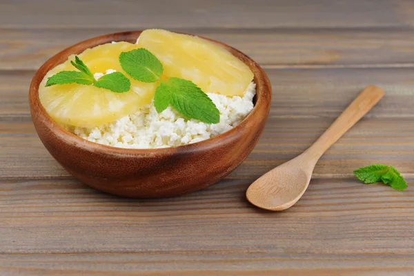 Bowl of tasty cottage cheese with pineapple on wooden table — Stock Photo, Image