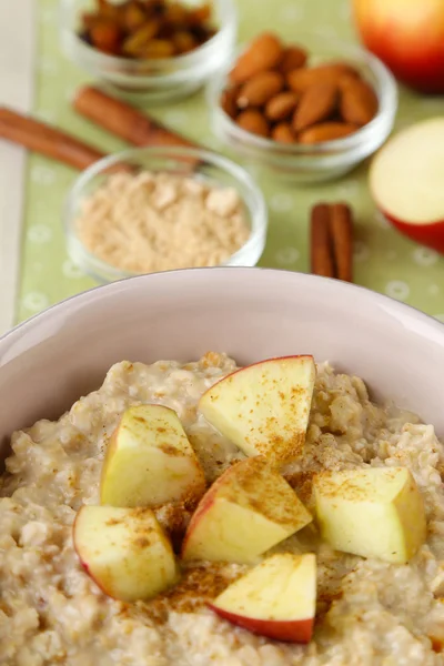 Tasty oatmeal with apples and cinnamon on table close up — Stock Photo, Image