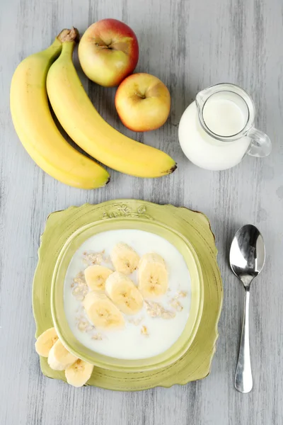 Fulgi de ovăz gustoși cu banane și lapte pe masă de lemn — Fotografie, imagine de stoc