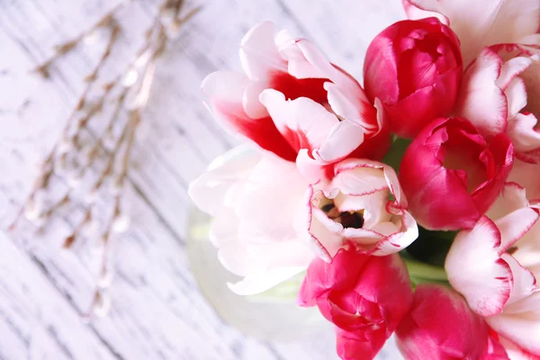 Piękne tulipany w dzbanku szkła na jasnym tle — Zdjęcie stockowe