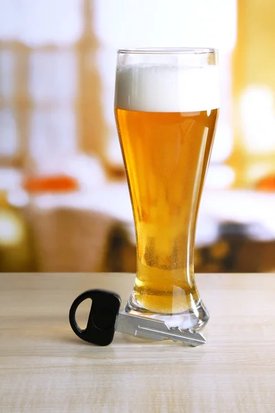Composição com chave de carro e copo de cerveja, na mesa de madeira, no fundo brilhante — Fotografia de Stock