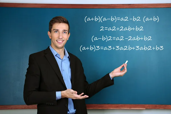 Young teacher near chalkboard in school classroom — Stock Photo, Image