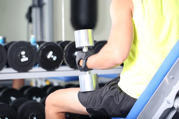 Man met halters op gym achtergrond close-up — Stockfoto