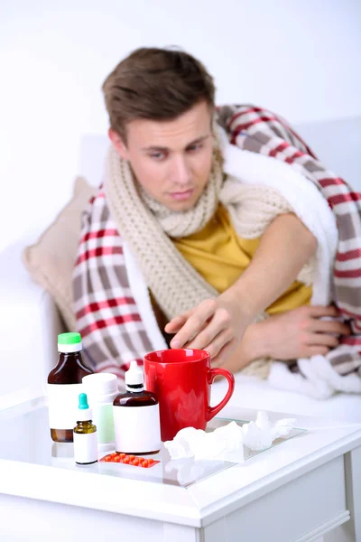 Guy wrapped in plaid lies on sofa is ill — Stock Photo, Image