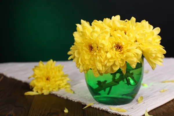 Lindas flores de crisântemo em vaso na mesa no fundo verde escuro — Fotografia de Stock