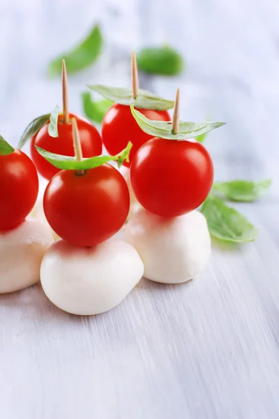 Ahşap masa üstünde domates ve fesleğen ile lezzetli mozzarella peyniri — Stok fotoğraf