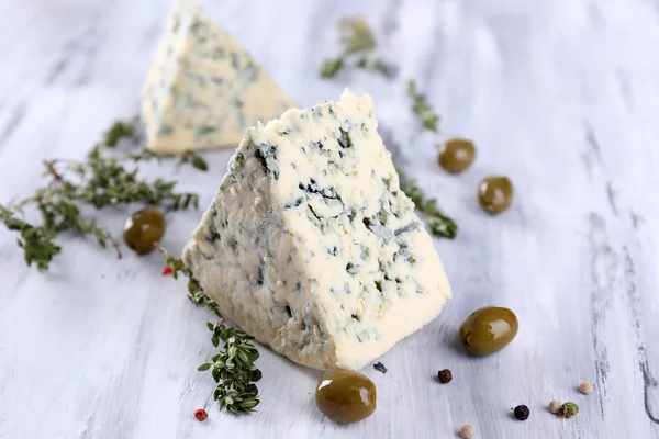 Tasty blue cheese with thyme and olives on wooden table — Stock Photo, Image