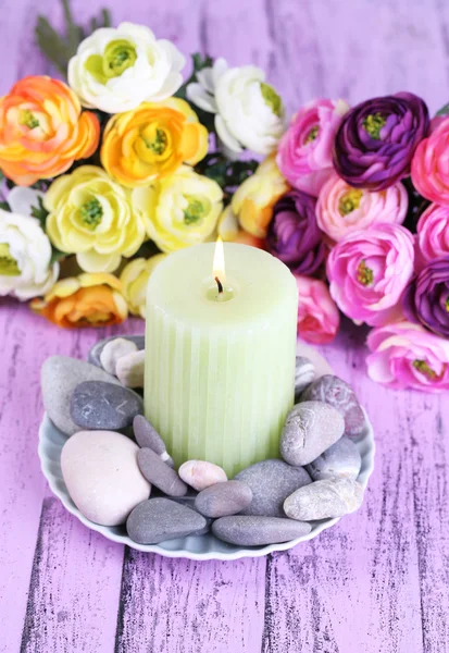 Composição com pedras de spa, vela e flores na mesa de madeira cor, no fundo claro — Fotografia de Stock