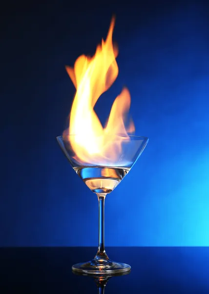 Sklo s hořící alkohol na modrém pozadí — Stock fotografie