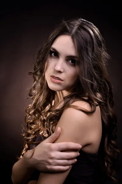 Piękna młoda kobieta z długimi włosami na ciemnym tle brązowy — Zdjęcie stockowe