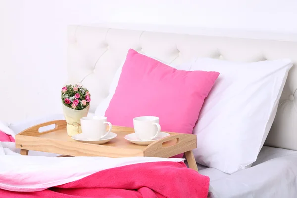 Cups of coffee on comfortable soft bed with pillows — Stock Photo, Image