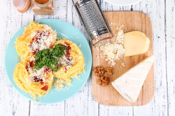 Composition with tasty spaghetti, grater, cheese, on wooden table background — Stock Photo, Image