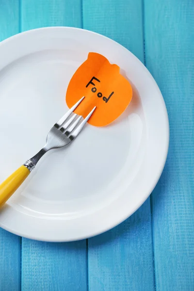 Note paper with message  attached to fork, on plate, on wooden background — Stock Photo, Image