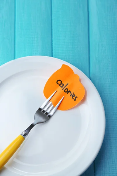 Note paper with message  attached to fork, on plate, on wooden background — Stock Photo, Image