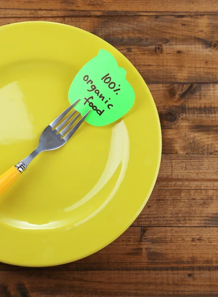 Note paper with message  attached to fork, on plate, on color wooden background — Stock Photo, Image