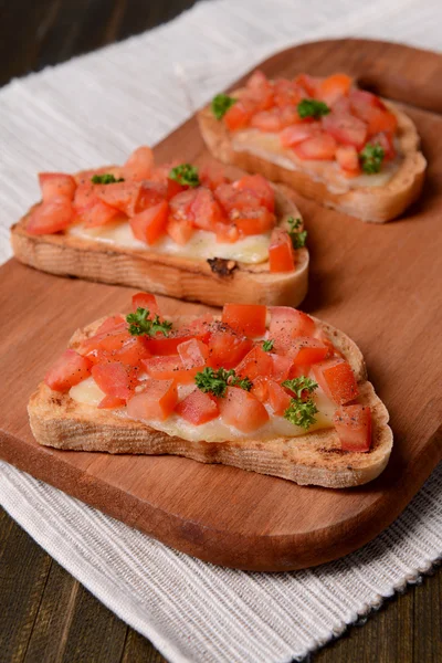 Delicious bruschetta with tomatoes on cutting board close-up — Stock Photo, Image