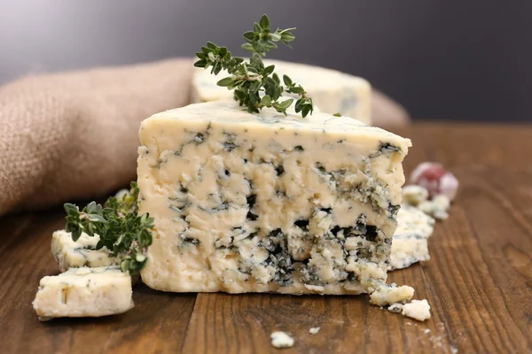 Queijo azul saboroso com tomilho, sobre mesa de madeira, sobre fundo cinza — Fotografia de Stock