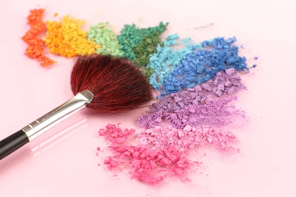 Arco iris triturado sombra de ojos y maquillaje profesional cepillo sobre fondo rosa — Foto de Stock