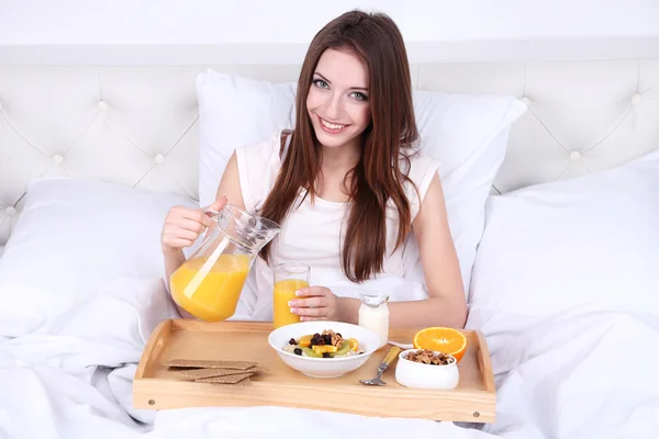 Junge schöne Frau im Bett mit leichtem Frühstück — Stockfoto