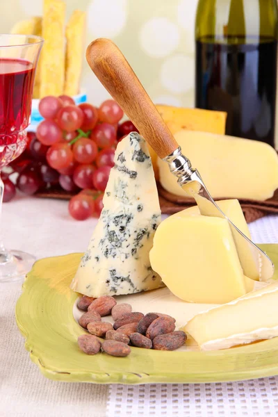 Placa de queso surtido, copa de uva y vino en la mesa, sobre fondo claro — Foto de Stock