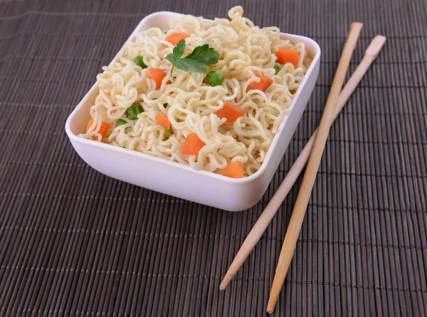 Macarrão instantâneo saboroso com legumes na tigela na mesa close-up — Fotografia de Stock