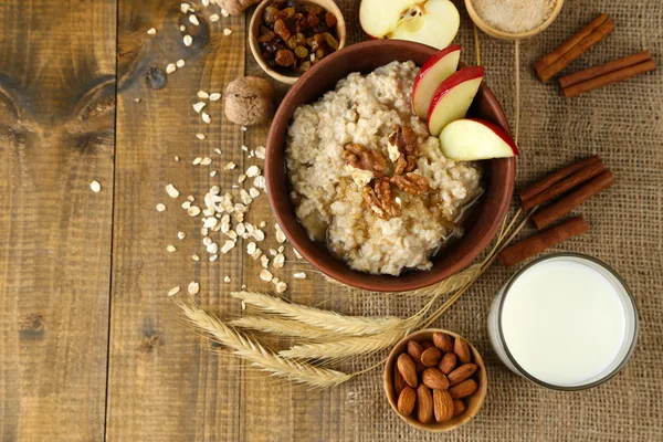 Tasty oatmeal with nuts and apples on wooden table