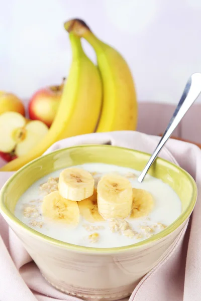 Tasty oatmeal with bananas and milk on table on bright background — Stock Photo, Image