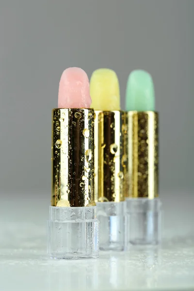 Hygienic lipsticks on grey background — Stock Photo, Image
