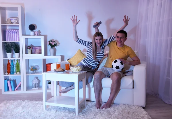 Ungt par tittar på TV hemma för SVÄRTNING ut — Stockfoto