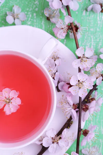 Fragrant tea with flowering branches on wooden table close-up — Stock Photo, Image