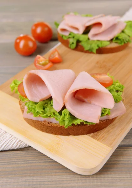Pyszne kanapki z sałatą i szynką na stole z bliska — Zdjęcie stockowe