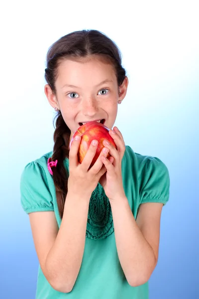 Porträtt av vacker liten flicka med apple på blå bakgrund — Stockfoto