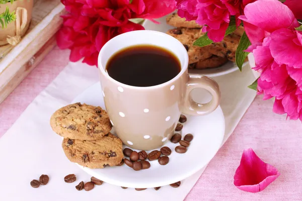 Taza de café, galletas y flores en la mesa en la cafetería —  Fotos de Stock