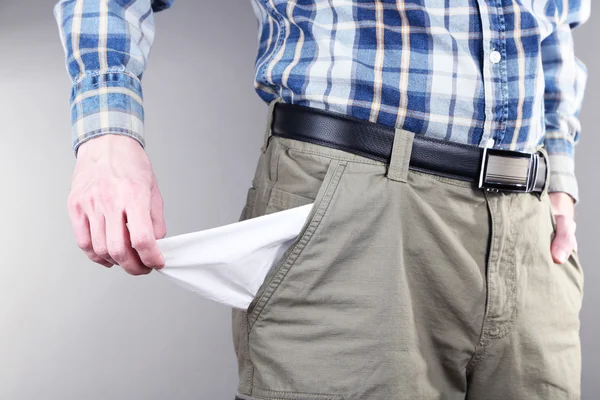 Hombre mostrando su bolsillo vacío sobre fondo gris —  Fotos de Stock